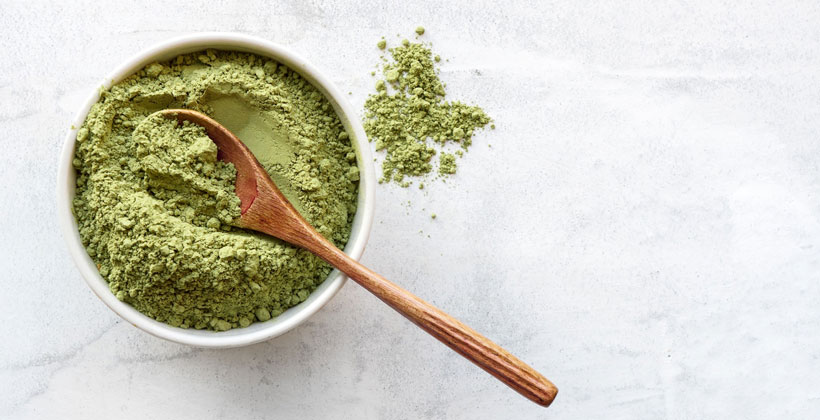 A bowl with Kratom powder and a wooden spoon