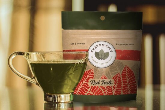 A cup of delicious kratom tea sits in front of a pouch of red indo kratom