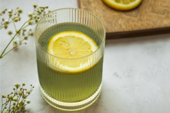 A glass of kratom tea with lemon and herbs