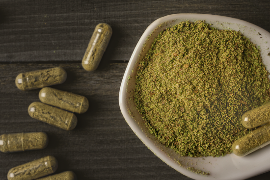 Kratom capsules on a gray wood table