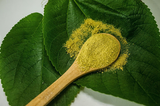 Green vein kratom powder pile on a leaf.
